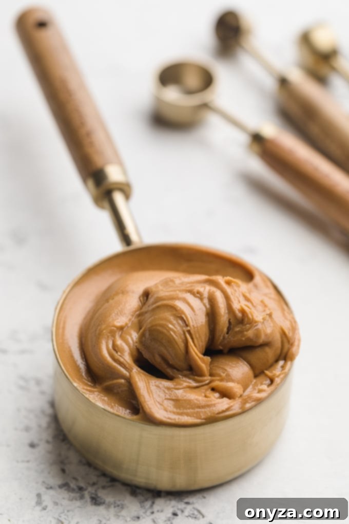 A measuring cup filled with Skippy's creamy peanut butter, emphasizing the smooth texture ideal for baking these cookies.