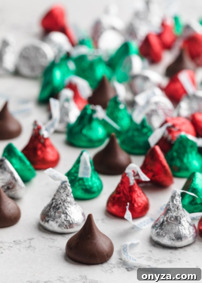 A pile of festive Holiday Hershey's milk chocolate kisses, unwrapped and ready to crown the warm peanut butter cookies.