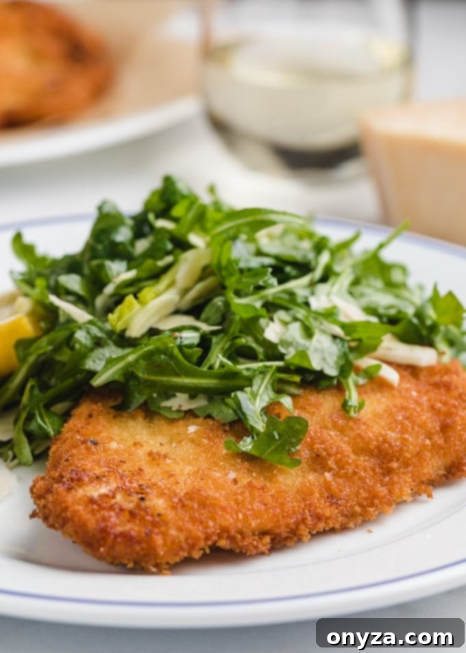 Stovetop and Air Fryer Chicken Milanese 2 chicken milanese on a white plate with arugula salad