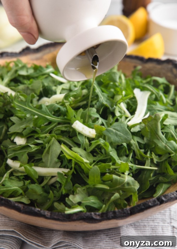 A stream of rich Greek extra virgin olive oil being gracefully drizzled over a fresh arugula salad in a rustic wooden bowl, highlighting the elegant simplicity of the dressing process.