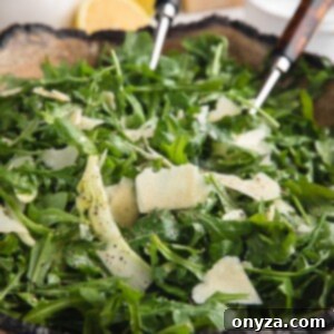 Arugula salad with shaved fennel and Parmigiano Reggiano in a beautiful wooden serving bowl, ready to be enjoyed.