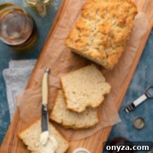 Sliced beer bread loaf on a wood serving board with butter and honey