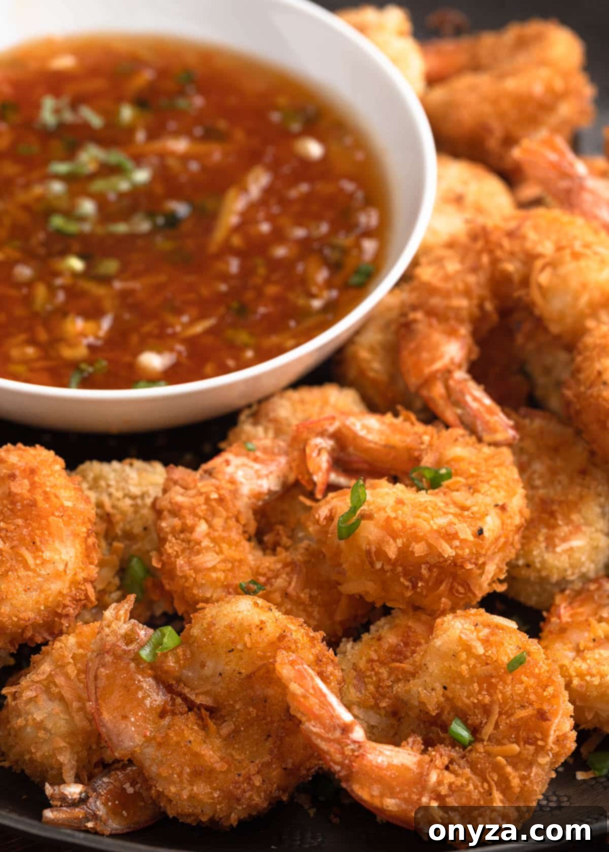 Tropical Crispy Prawns 12 A vibrant serving platter laden with golden coconut shrimp, accompanied by a small bowl of spicy orange chili dipping sauce, inviting guests to indulge.