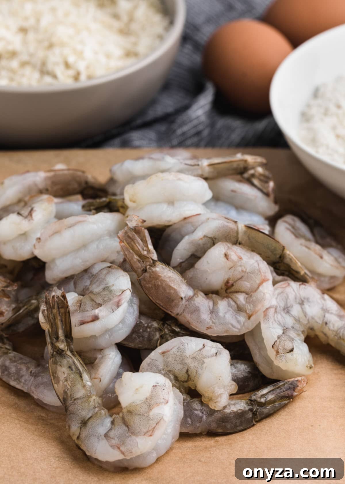 Tropical Crispy Prawns 3 Raw, cleaned 16/20 count shrimp ready for breading, displayed alongside bowls of shredded coconut and flour.