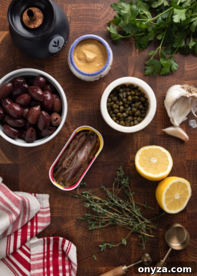 Savory Olive Spread 3 overhead photo of olives, capers, anchovies, lemon wedges, herbs, garlic, and Dijon mustard