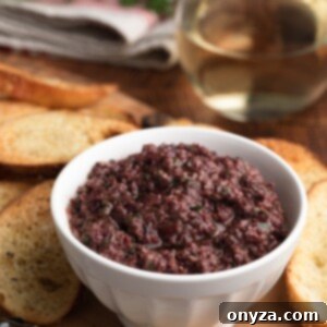 Savory Olive Spread 7 black olive tapenade in a white bowl on a serving board with crostini