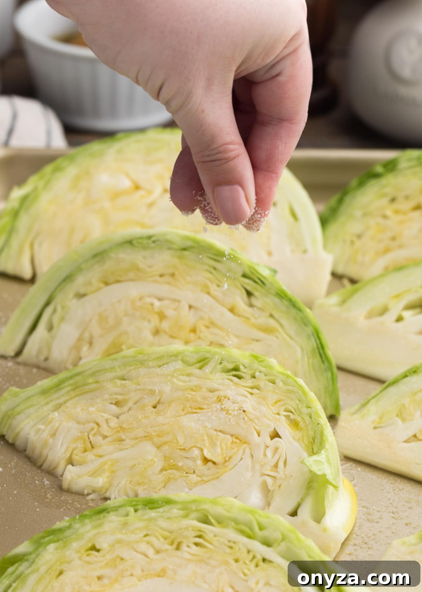 sprinkling kosher salt onto cabbage wedges on a roasting pan