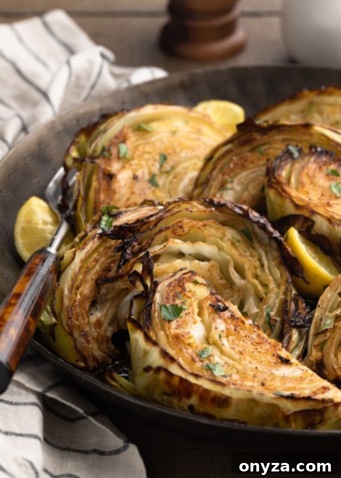 closeup of roasted cabbage wedges in a serving bowl with lemons and chopped parsley
