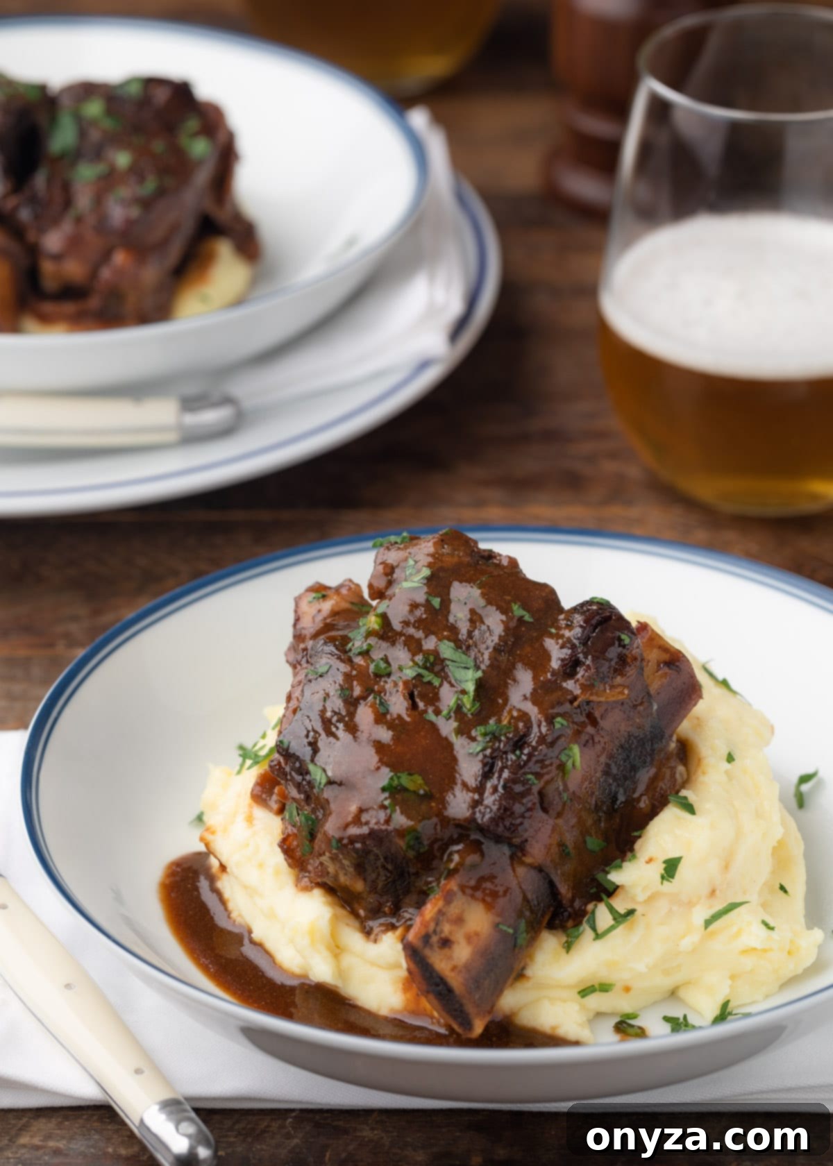 Stout Beer Braised Short Rib in a white serving bowl over creamy mashed potatoes