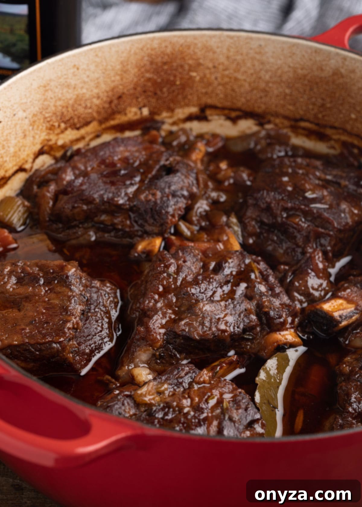 Cooked stout beer braised short ribs in a red Dutch oven, showcasing their tender perfection