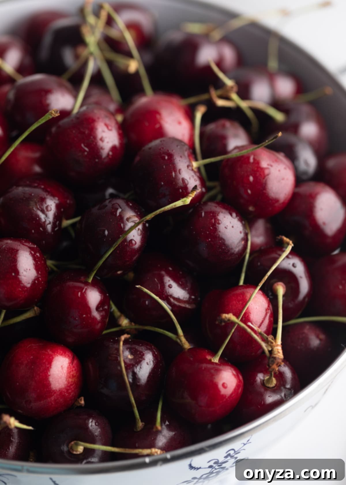 Closeup photo of fresh Bing cherries in a white enameled colander.