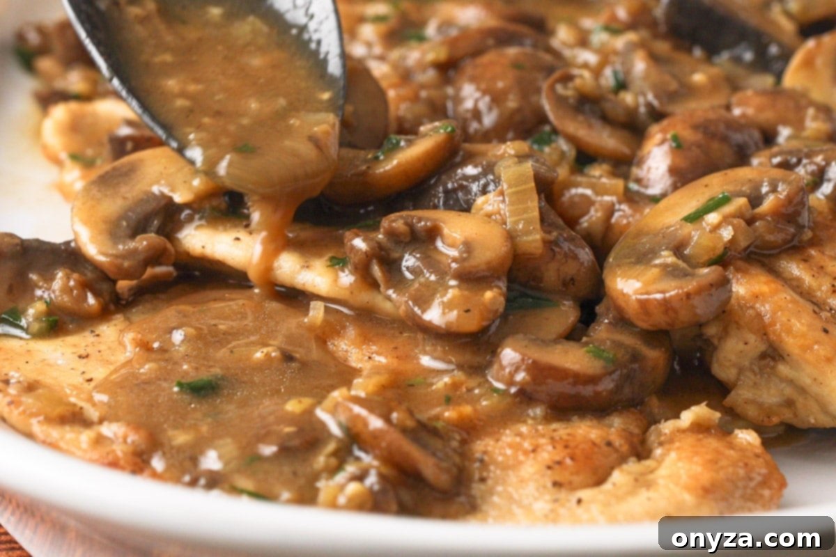 Spoonfuls of rich Marsala sauce and sautéed mushrooms being carefully ladled over golden-brown chicken cutlets arranged on an elegant serving platter.