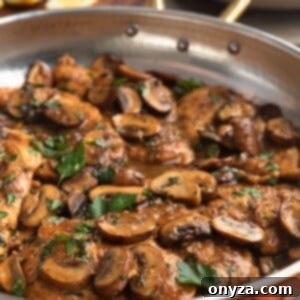 Side view of chicken marsala in a copper frying pan, showcasing the rich sauce and tender chicken.