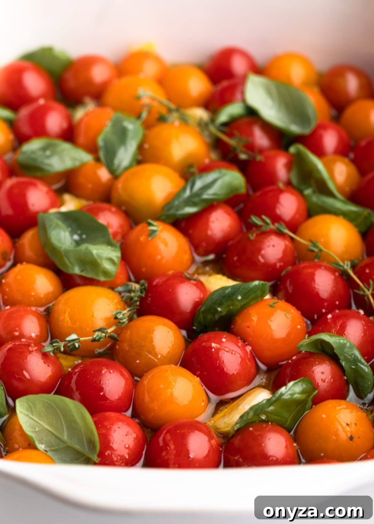 Garlic Herb Cherry Tomato Confit 5 cherry tomatoes in a white ceramic baking dish with olive oil, garlic, and fresh herbs