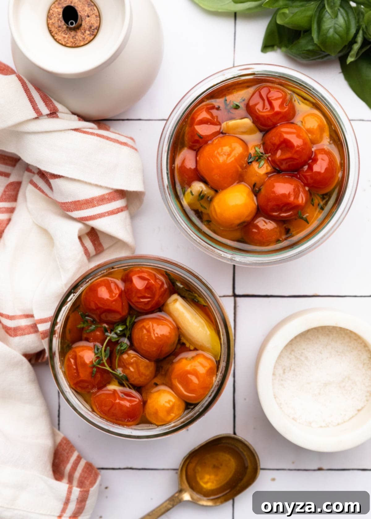 Garlic Herb Cherry Tomato Confit 7 overhead of two jars of cherry tomato confit on a white tile board
