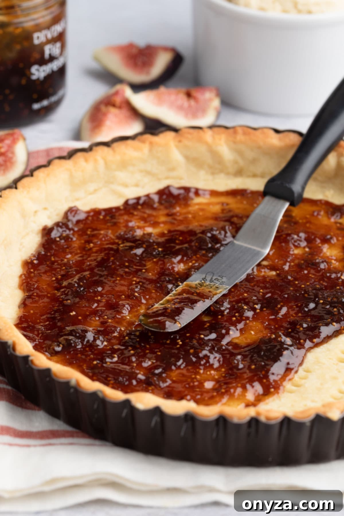 fig spread in a par-baked tart shell with a metal spreader