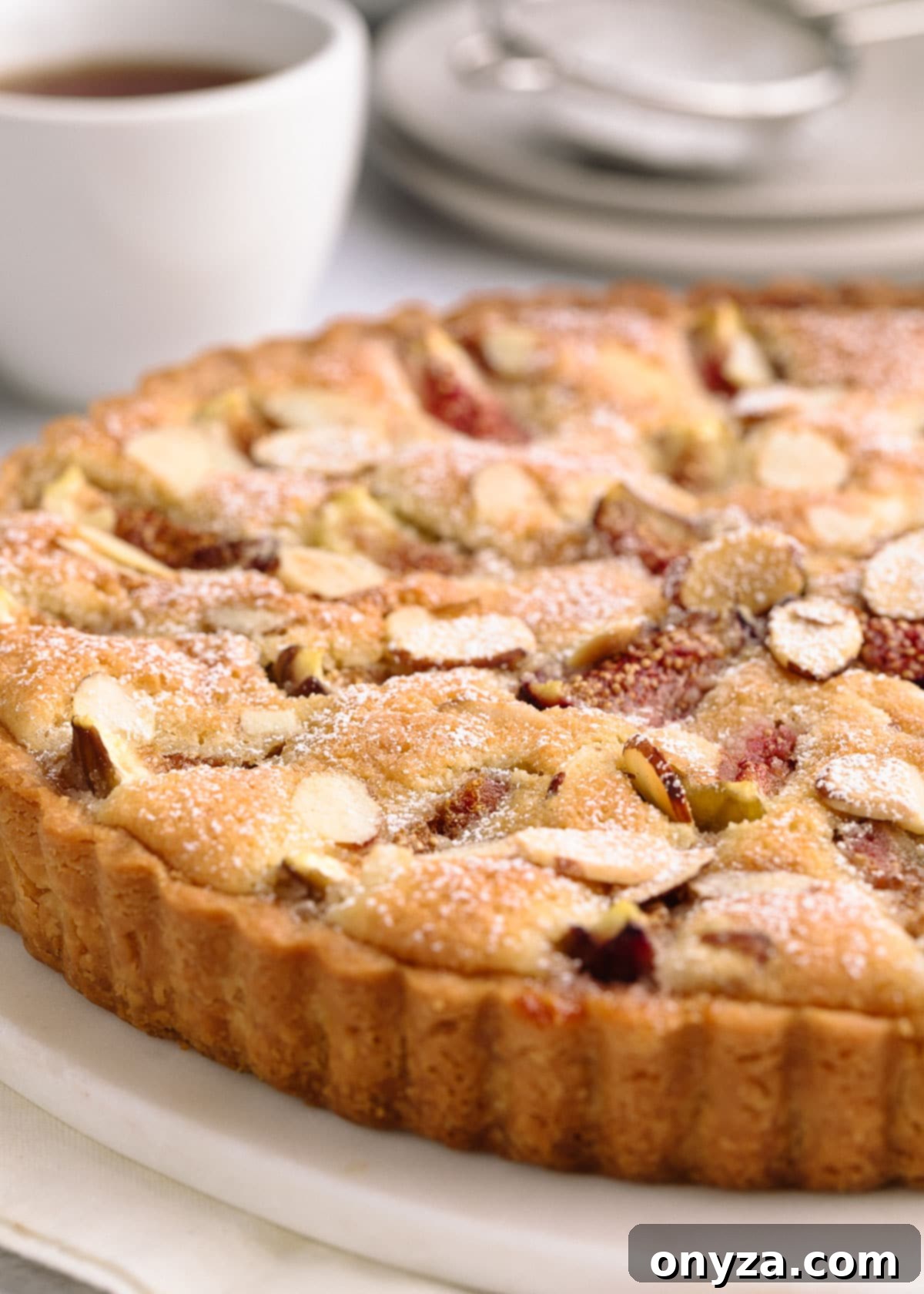 side view of a baked fig and almond cream tart on a white marble board