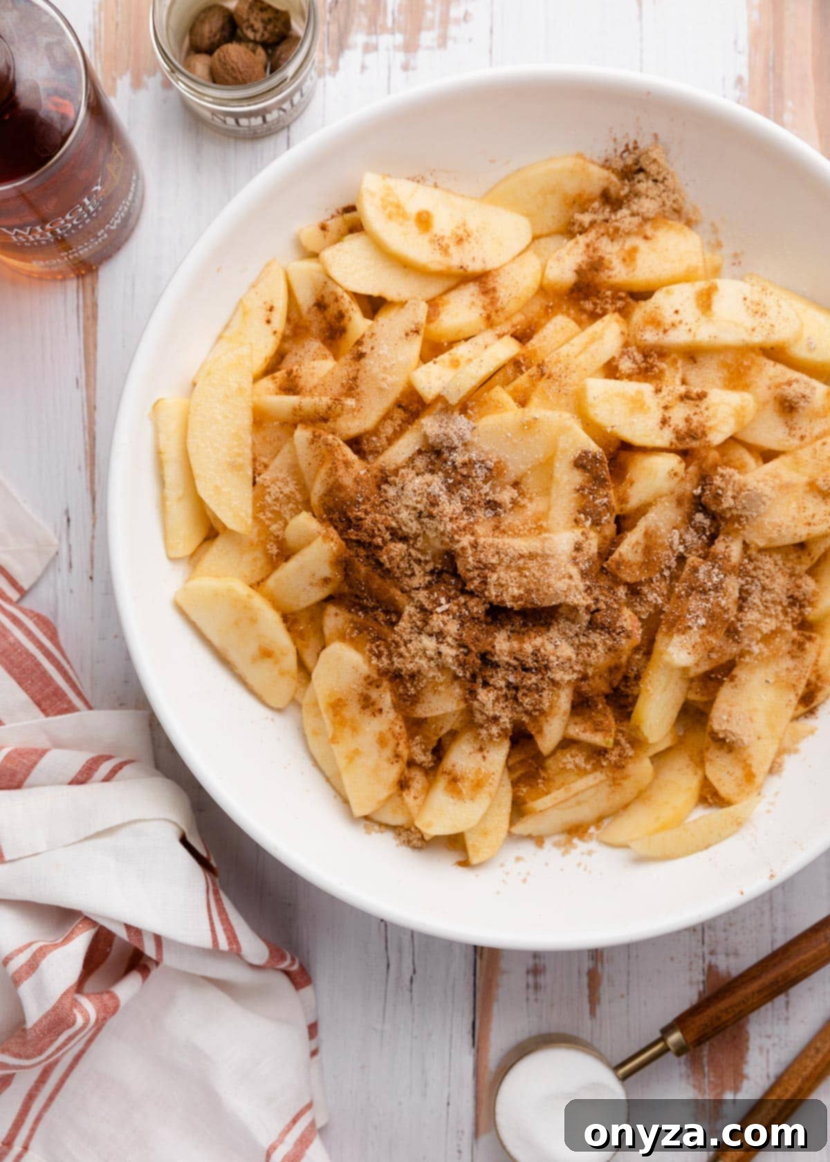Close-up of freshly sliced Honeycrisp apples in a white bowl, generously dusted with cinnamon and brown sugar, ready to be mixed for the crisp filling.