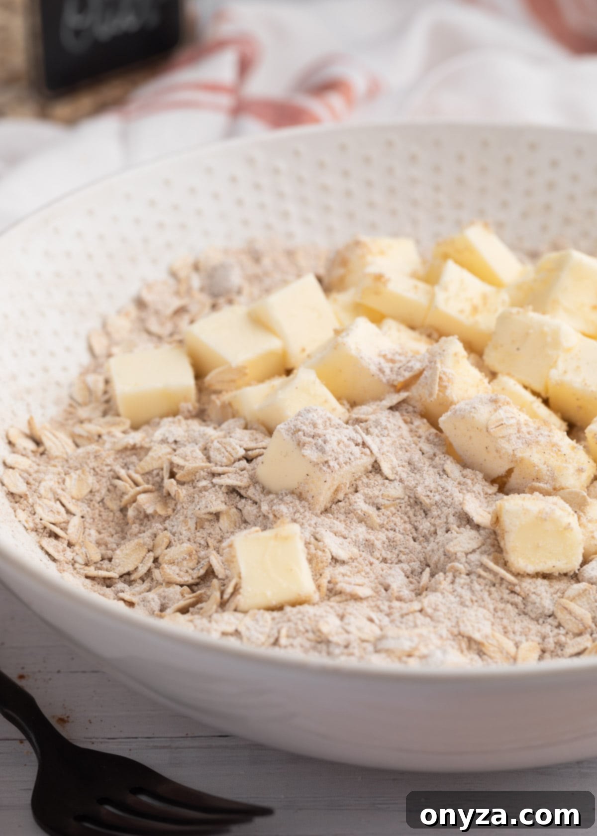 Cubed, softened butter nestled in a bowl with brown sugar, oats, and flour – the key ingredients for the rich, crumbly crisp topping.
