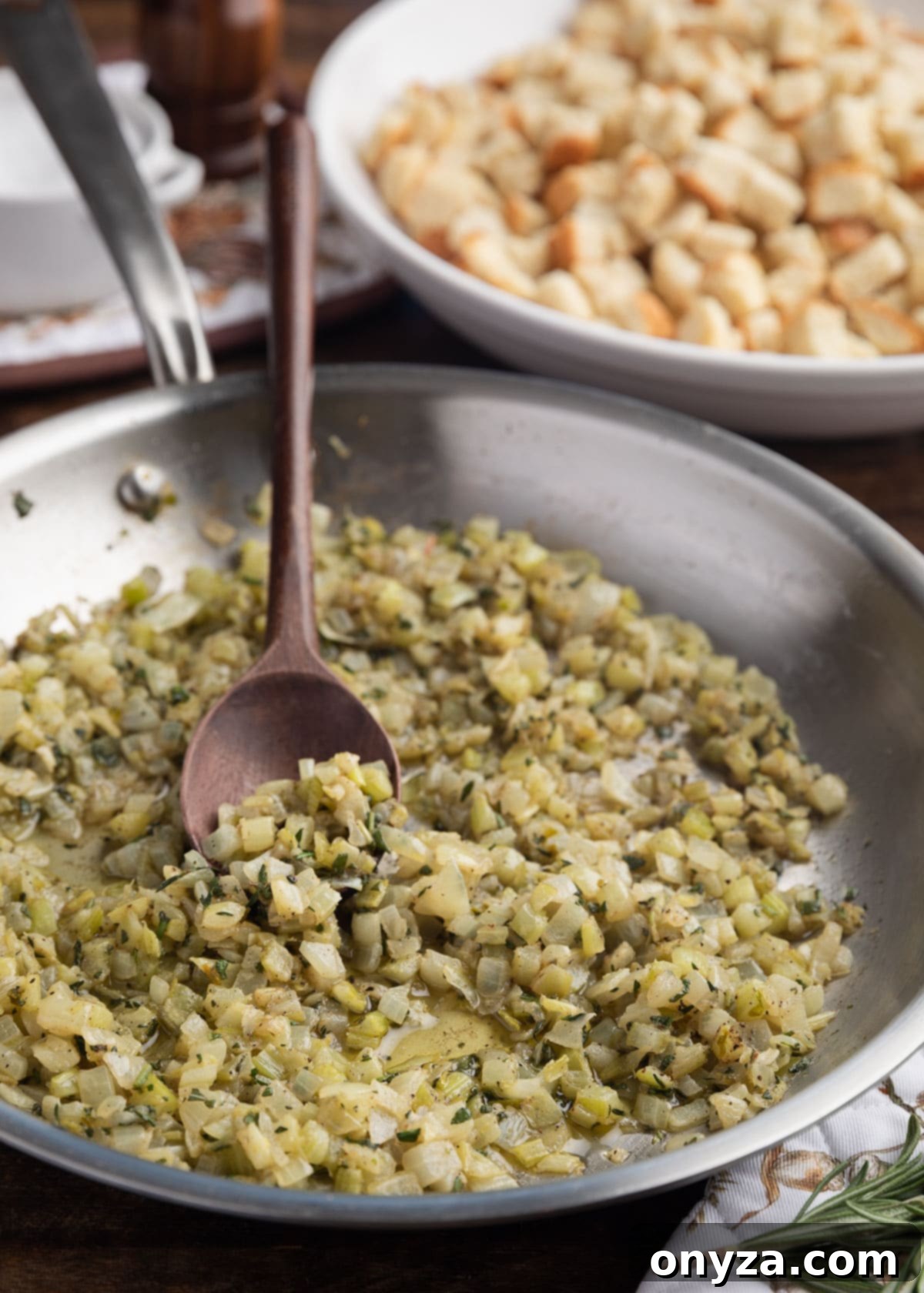 Sautéed celery and onions gently cooked with a blend of fragrant fresh herbs in a stainless steel skillet, ready to be incorporated into the stuffing mixture.