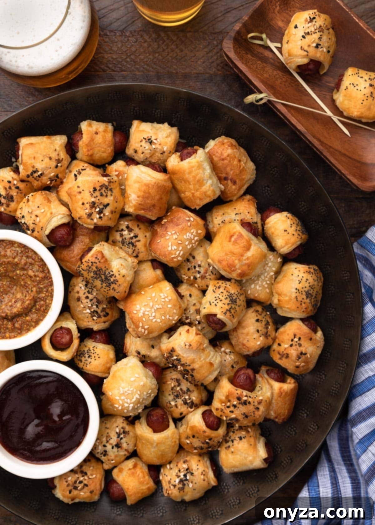 Overhead shot of pigs in a blanket on a round serving platter with various dipping sauces