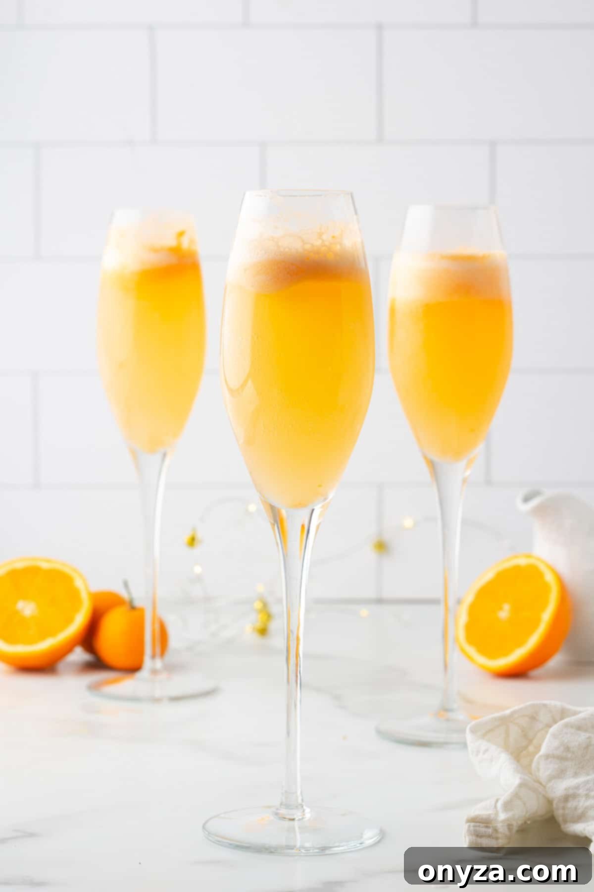 three orange sherbet mimosa mocktails in champagne flutes