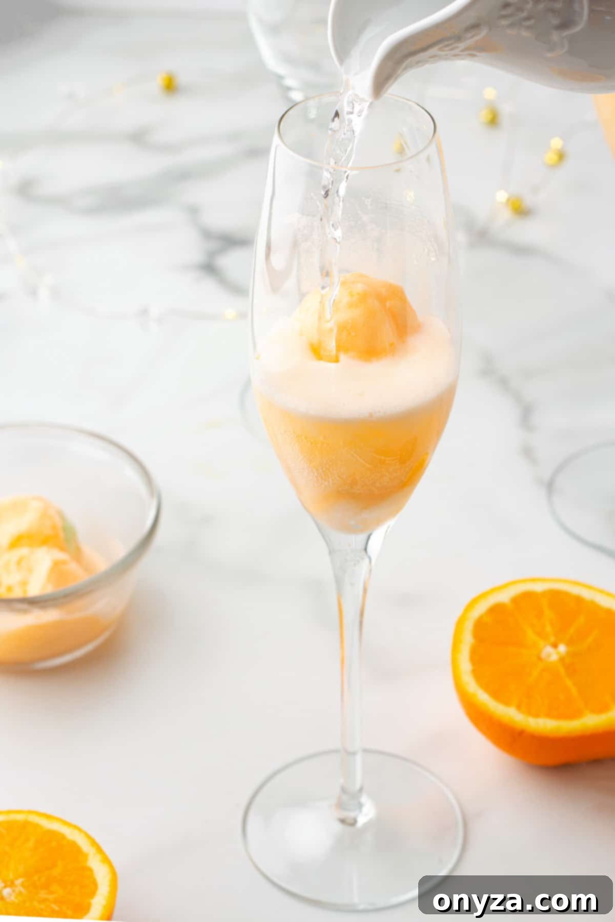 pouring sparkling water into a champagne flute with a scoop of orange sherbet