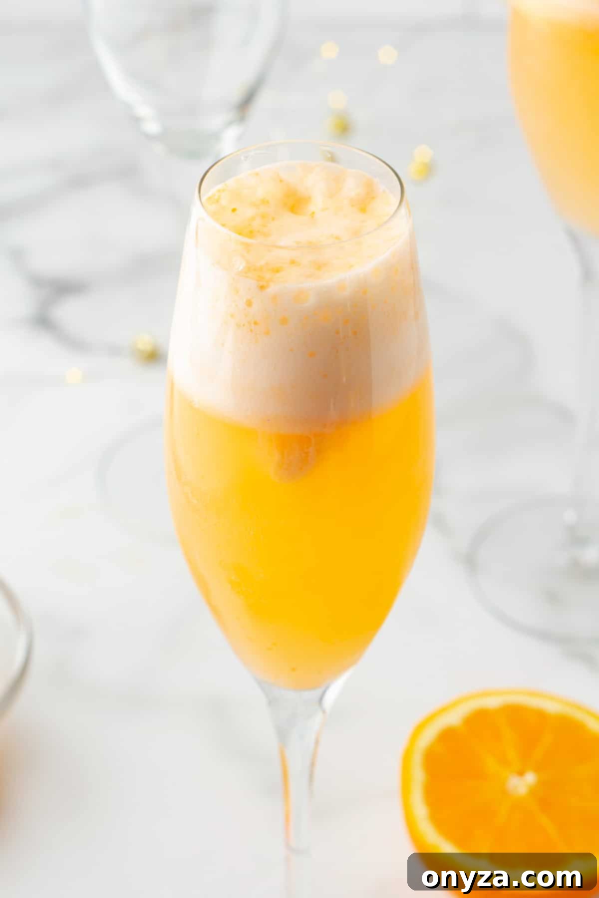 side view of an orange sherbet mimosa mocktail in a champagne flute