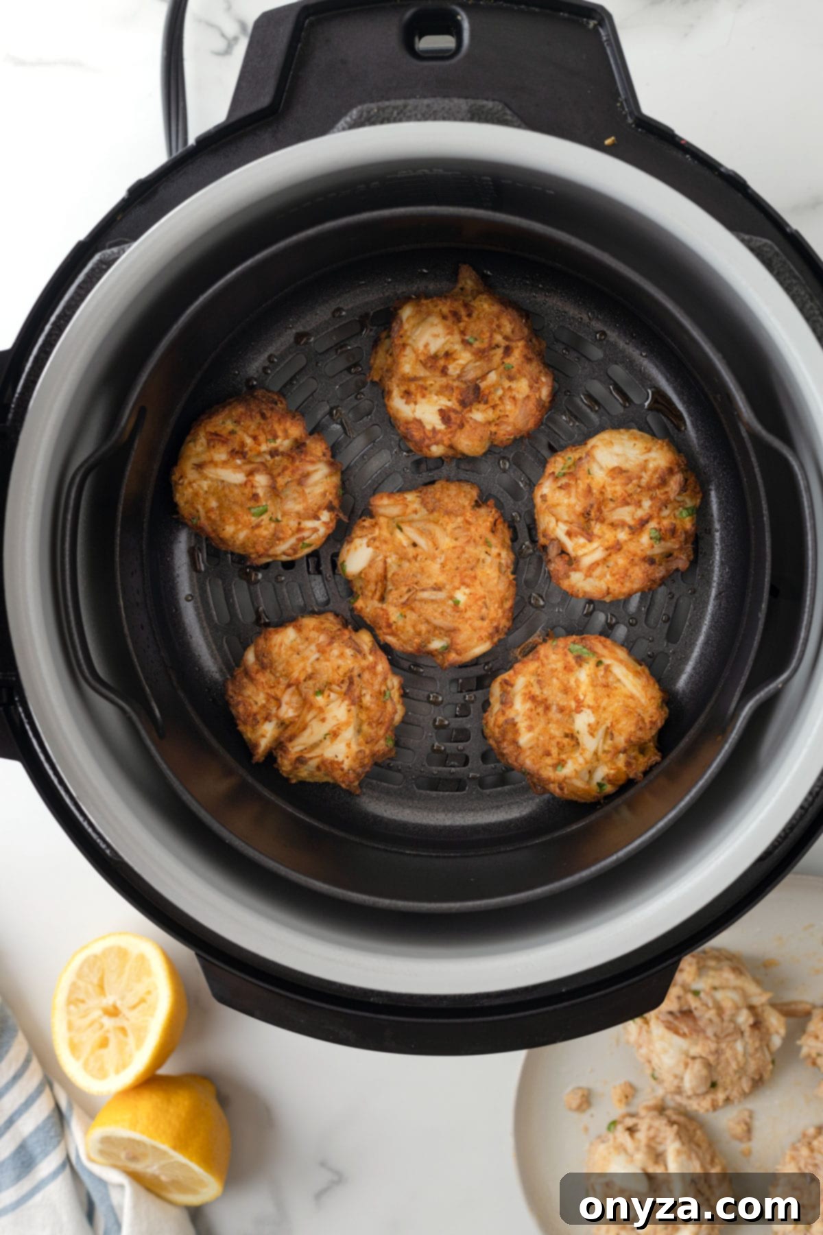 Overhead view of perfectly cooked golden-brown air fried crab cakes resting in an air fryer basket.