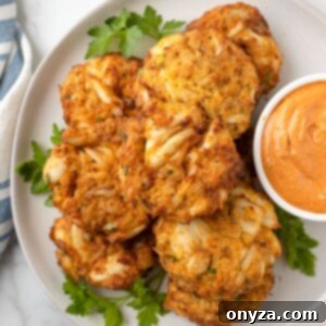 overhead photo of air fried crab cakes on a white plate with a bowl of remoulade