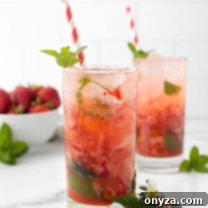 Two Strawberry Mojitos in highball glasses, garnished with red and white paper straws, fresh strawberries, and mint sprigs.