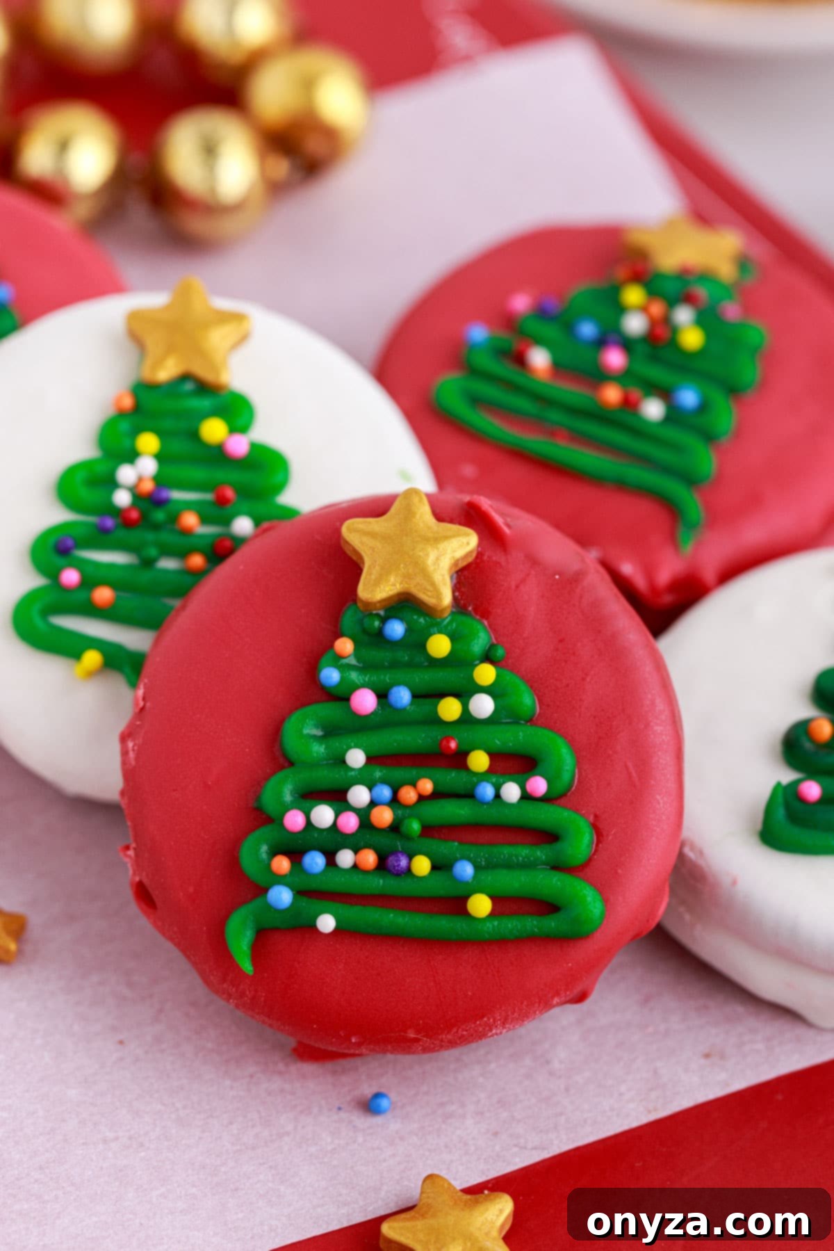 red and white candy coated oreos with christmas tree decorations on a parchment-lined platter