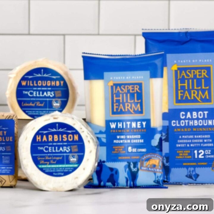 A selection of five artisan cheeses from Jasper Hill Farm arranged on a wooden board.