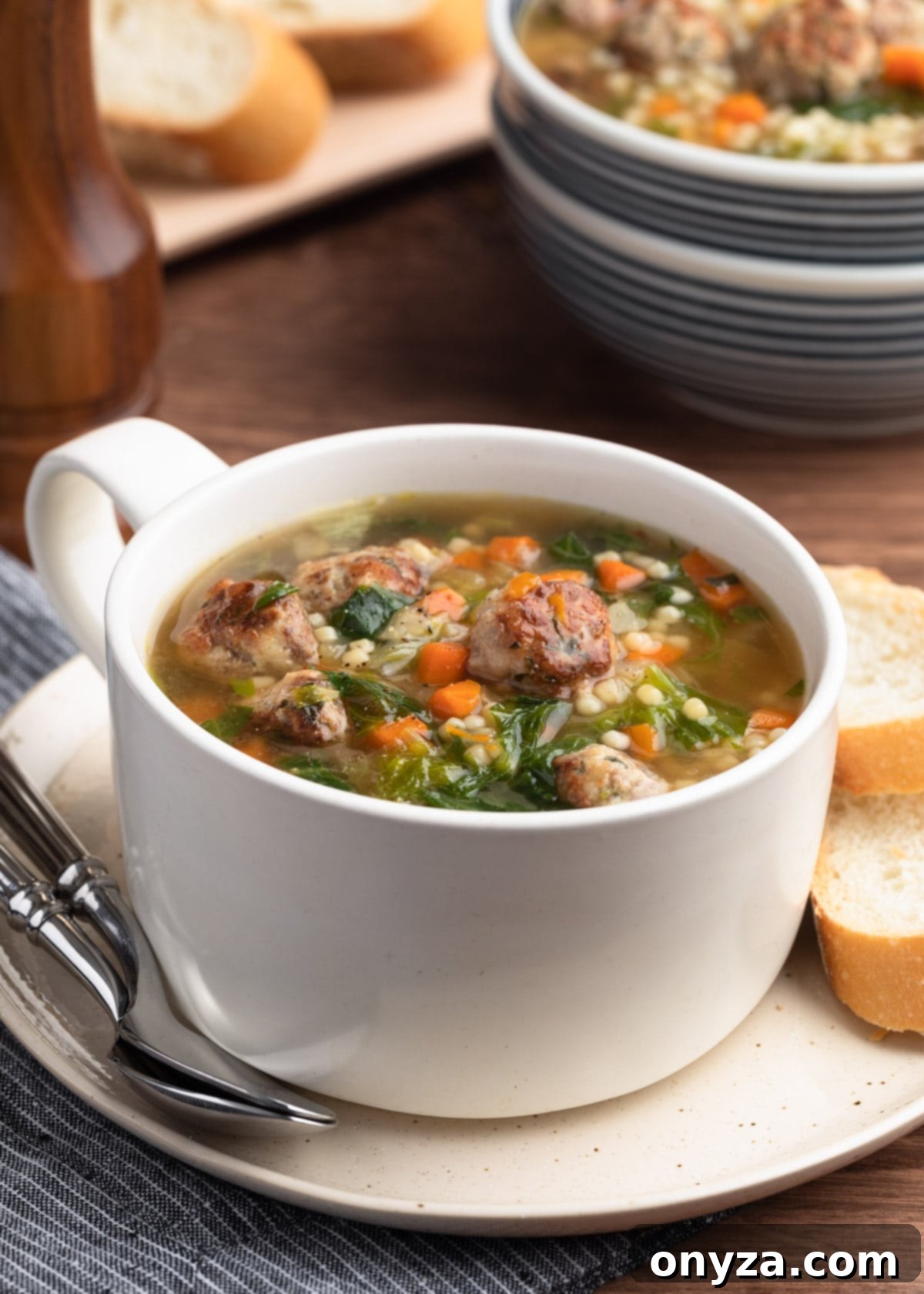 A steaming bowl of homemade Italian Wedding Soup with small meatballs, pasta, and escarole, garnished with fresh parsley.