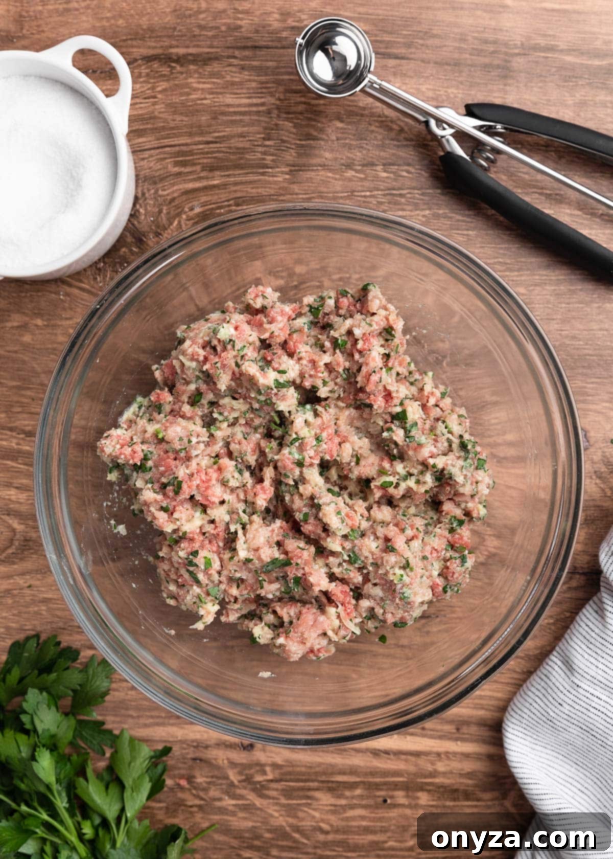 Uncooked, gently mixed meatball mixture in a glass bowl, perfectly seasoned and ready for shaping.