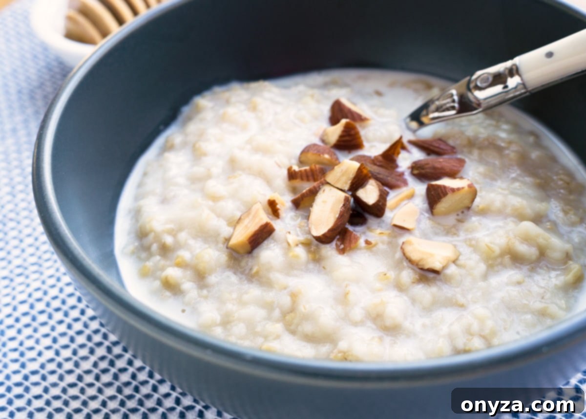 A deep blue bowl filled with hearty steel-cut oats, beautifully garnished with chopped almonds and a drizzle of warm cardamom milk, presenting a comforting and nutritious breakfast option.