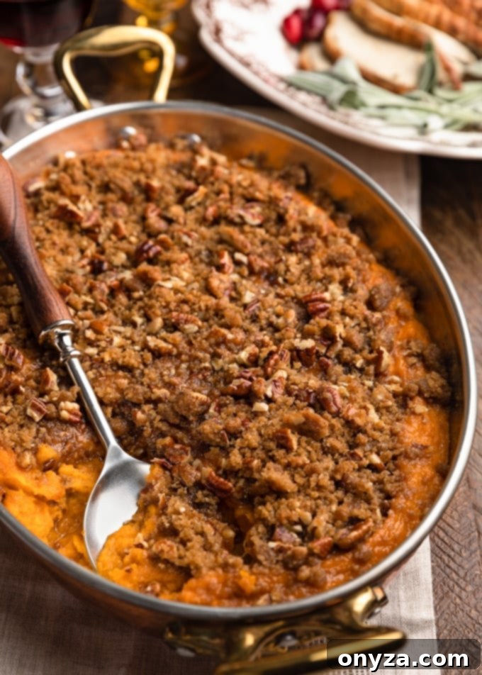 buttermilk sweet potato casserole in a copper gratin dish with a serving spoon