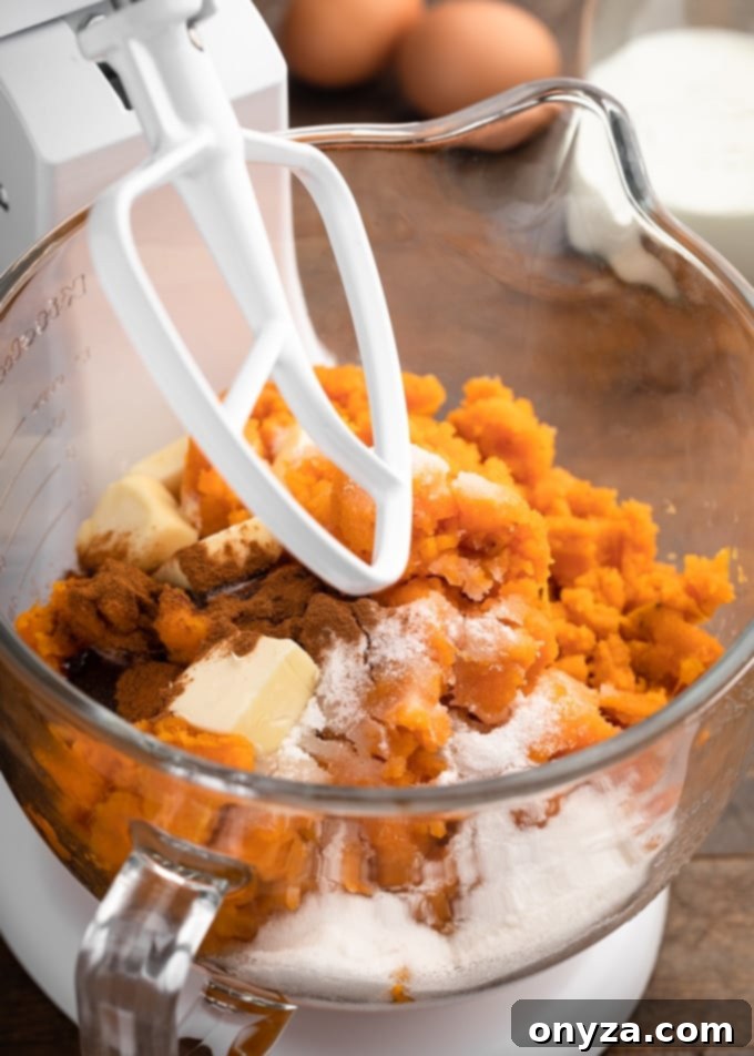 sweet potatoes in a white stand mixer with butter, sugar, and cinnamon