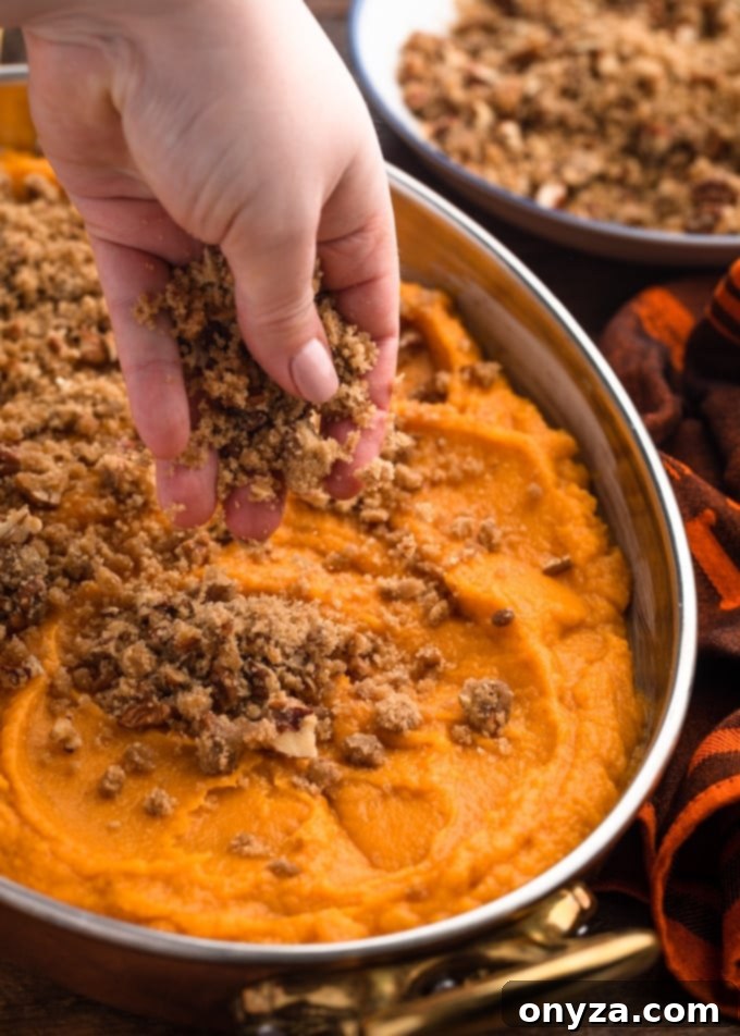 sprinkling pecan streusel topping over an unbaked sweet potato casserole