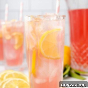 Two glasses of pink lemonade with lemon slices and pink striped paper straws, a perfect refreshing drink.