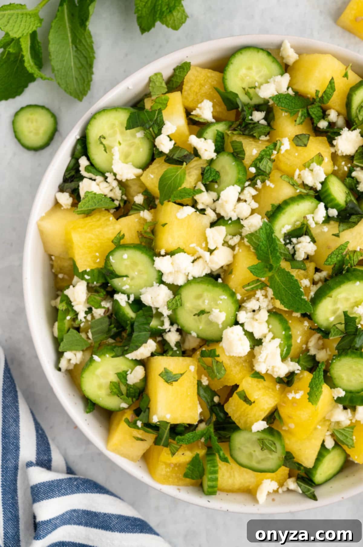 A vibrant overhead closeup of a Watermelon and Feta Salad, showcasing the juicy fruit, crumbled cheese, and fresh herbs in a simple white bowl, highlighting its refreshing appeal.