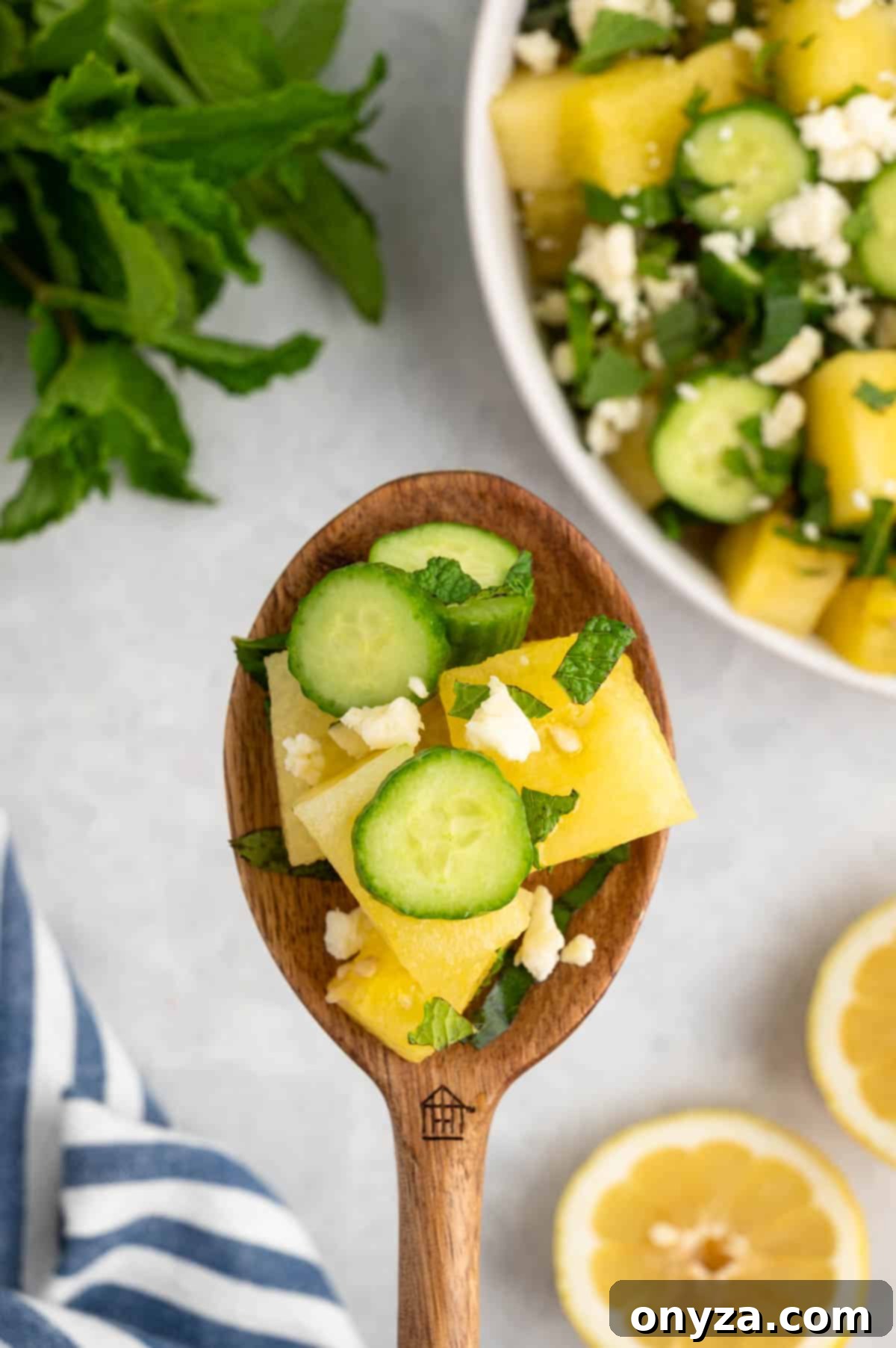 A single wooden spoon holds a perfect scoop of Watermelon Feta Salad, highlighting its vibrant colors and refreshing texture.