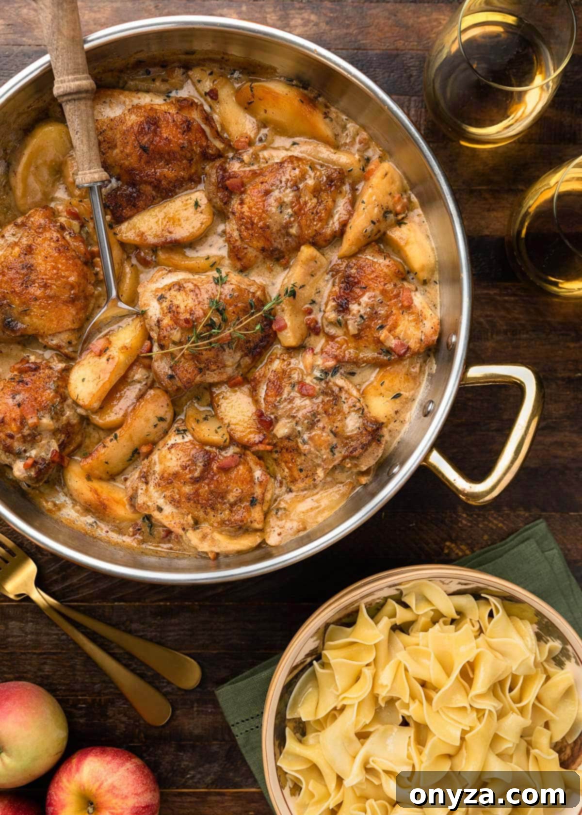 Cider-Braised Chicken with Crispy Bacon and Apples 2 Crispy chicken thighs and tender apples simmering in a rich hard cider sauce alongside a bowl of egg noodles, ready to be served as a comforting fall meal.