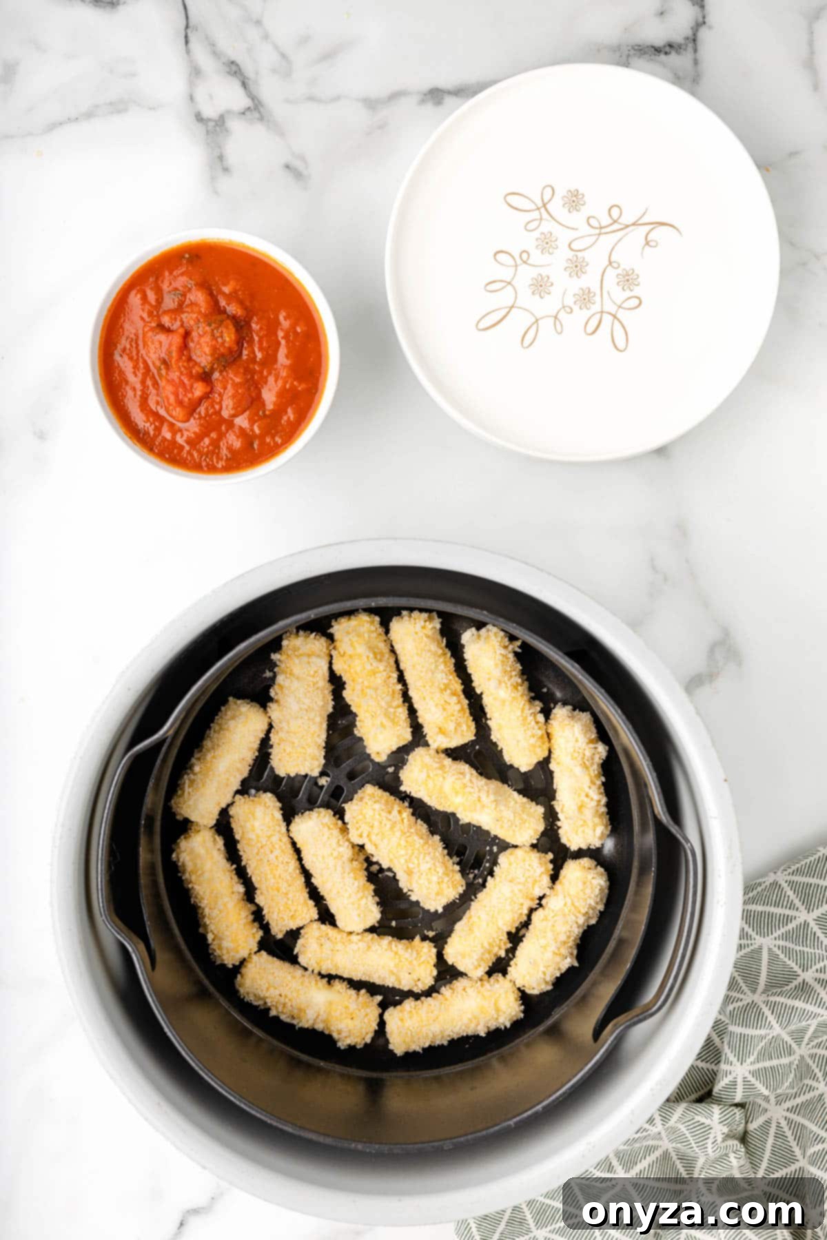 Overhead shot of perfectly breaded mozzarella sticks nestled in an air fryer basket, ready for cooking.