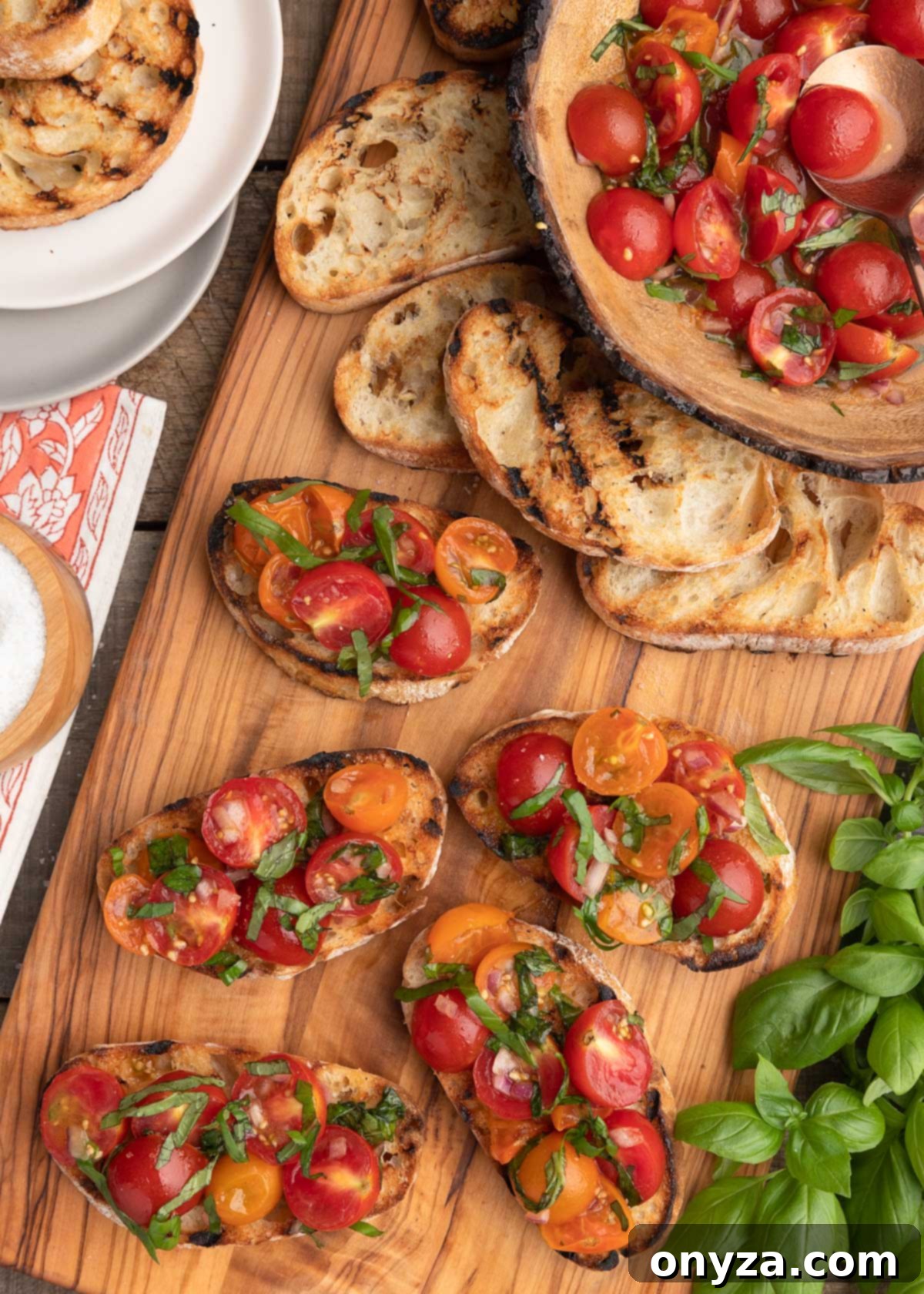 Fresh Cherry Tomato Bruschetta 10 overhead photo of cherry tomato bruschetta toasts on a wooden serving board, with a bowl of tomato topping