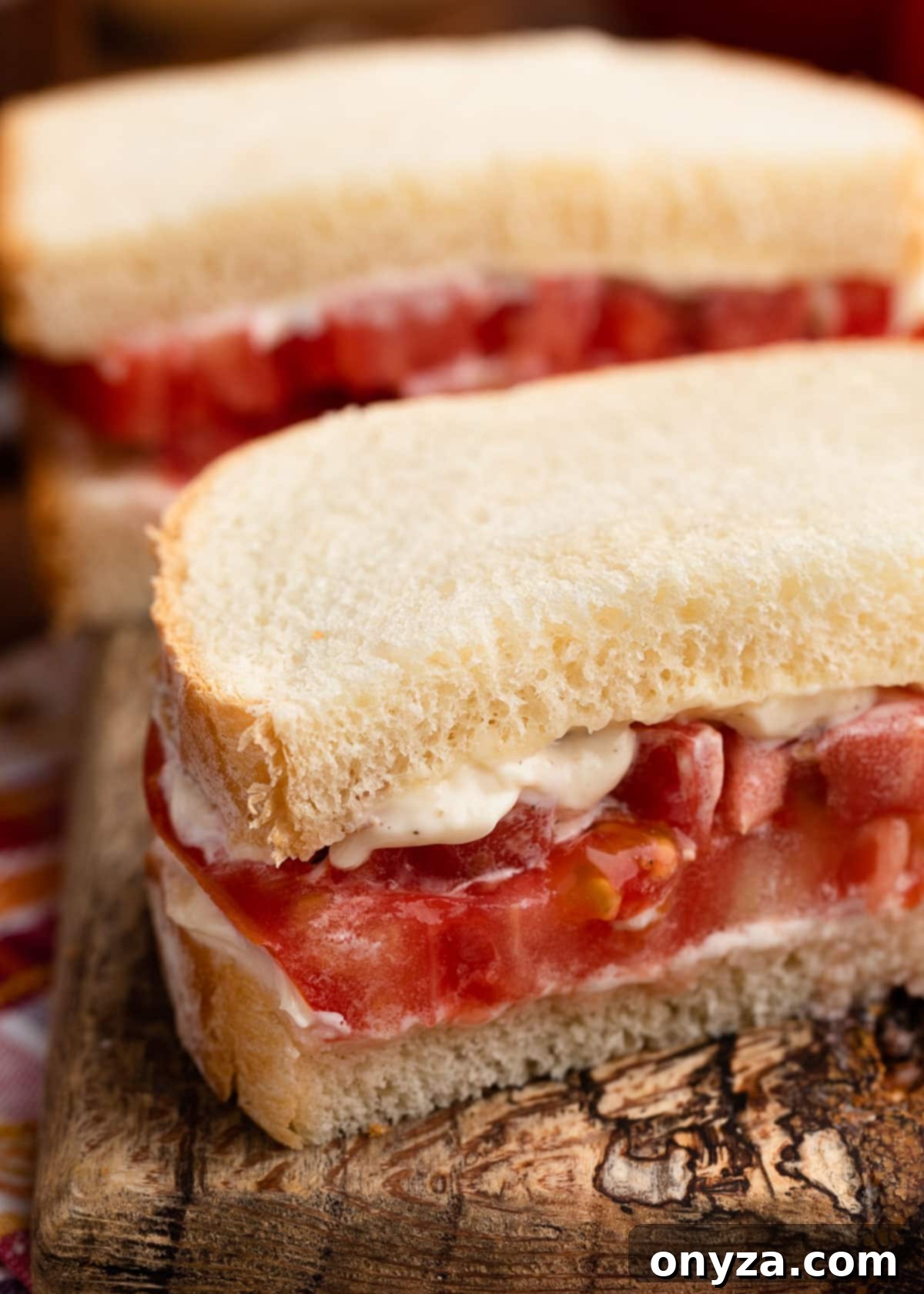 Sun-Kissed Southern Tomato Sandwich 8 Close-up of a perfectly cut Southern Tomato Sandwich on a rustic wooden serving board, showcasing the juicy tomato and creamy mayonnaise
