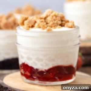 No-Bake Graham Cheesecake Delights 8 A beautiful strawberry cheesecake crumble dessert jar on a wooden trivet, ready to be enjoyed.