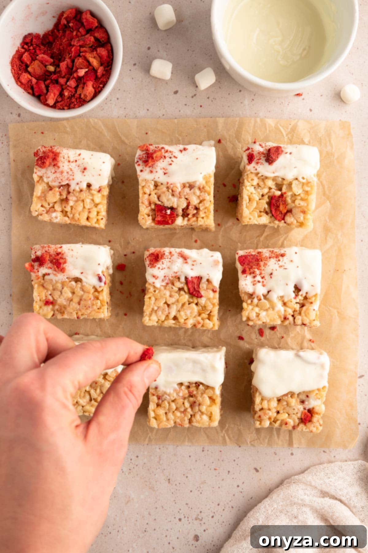 Sweet Strawberry Krispie Delights 11 Sprinkling delicate crushed freeze-dried strawberries over white chocolate-dipped Krispie treats, arranged on a sheet of parchment paper for setting