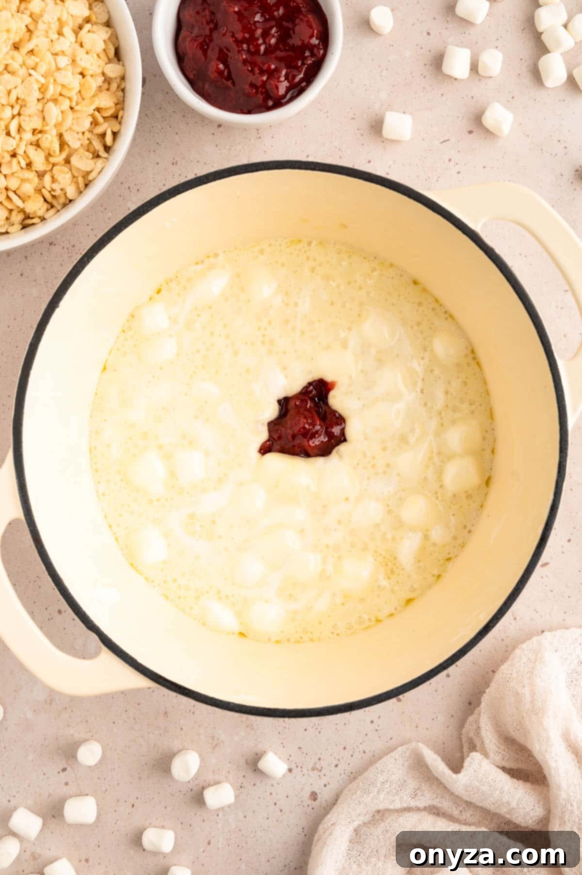 Sweet Strawberry Krispie Delights 5 Overhead photo capturing the vibrant mixture of melted marshmallows and sweet strawberry preserves swirling in a white enameled cast iron pot