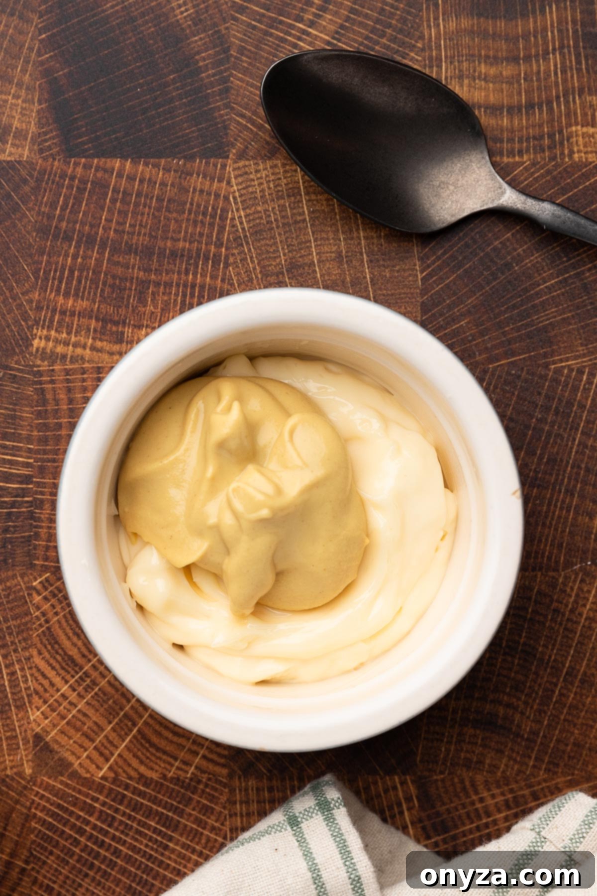 overhead photo of a bowl of mayonnaise and Dijon mustard on a butcher block board